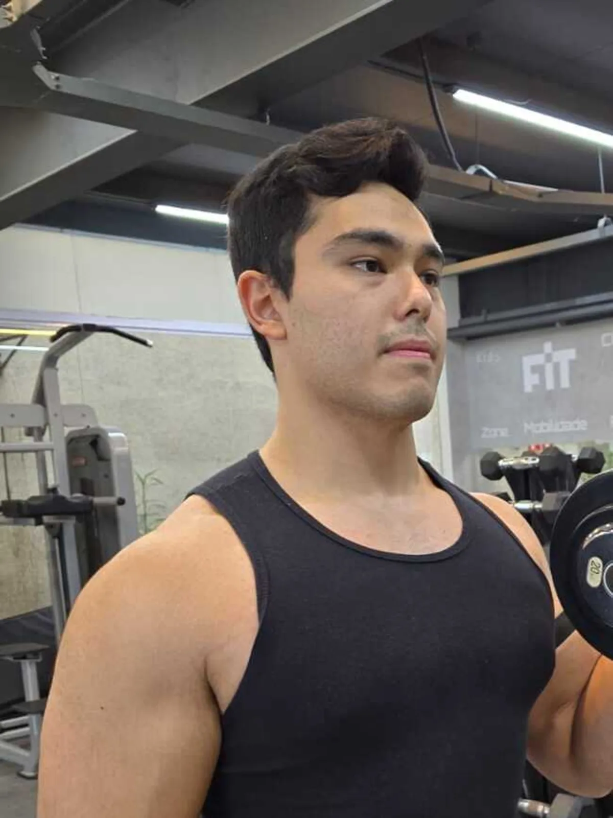 Lucas demonstrando a execução de rosca com halter durante um treino